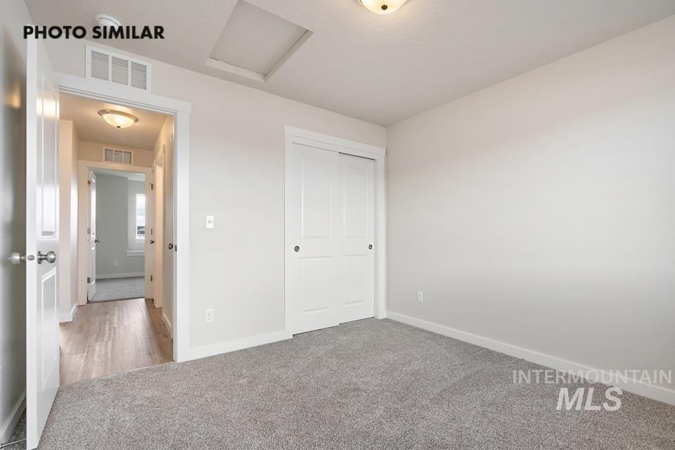 Unfurnished bedroom featuring attic access, carpet flooring, and a closet