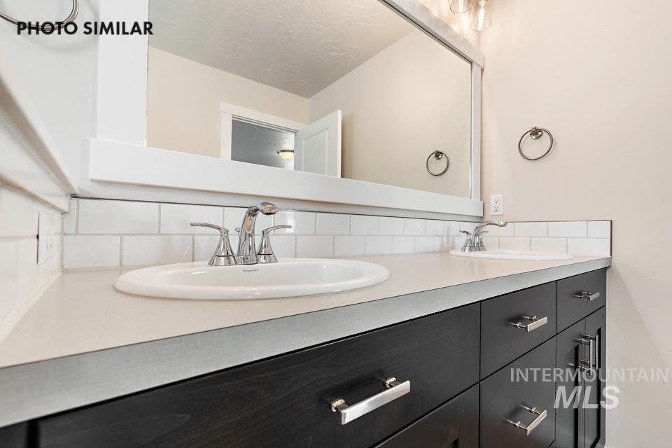 Full bathroom featuring double vanity and backsplash