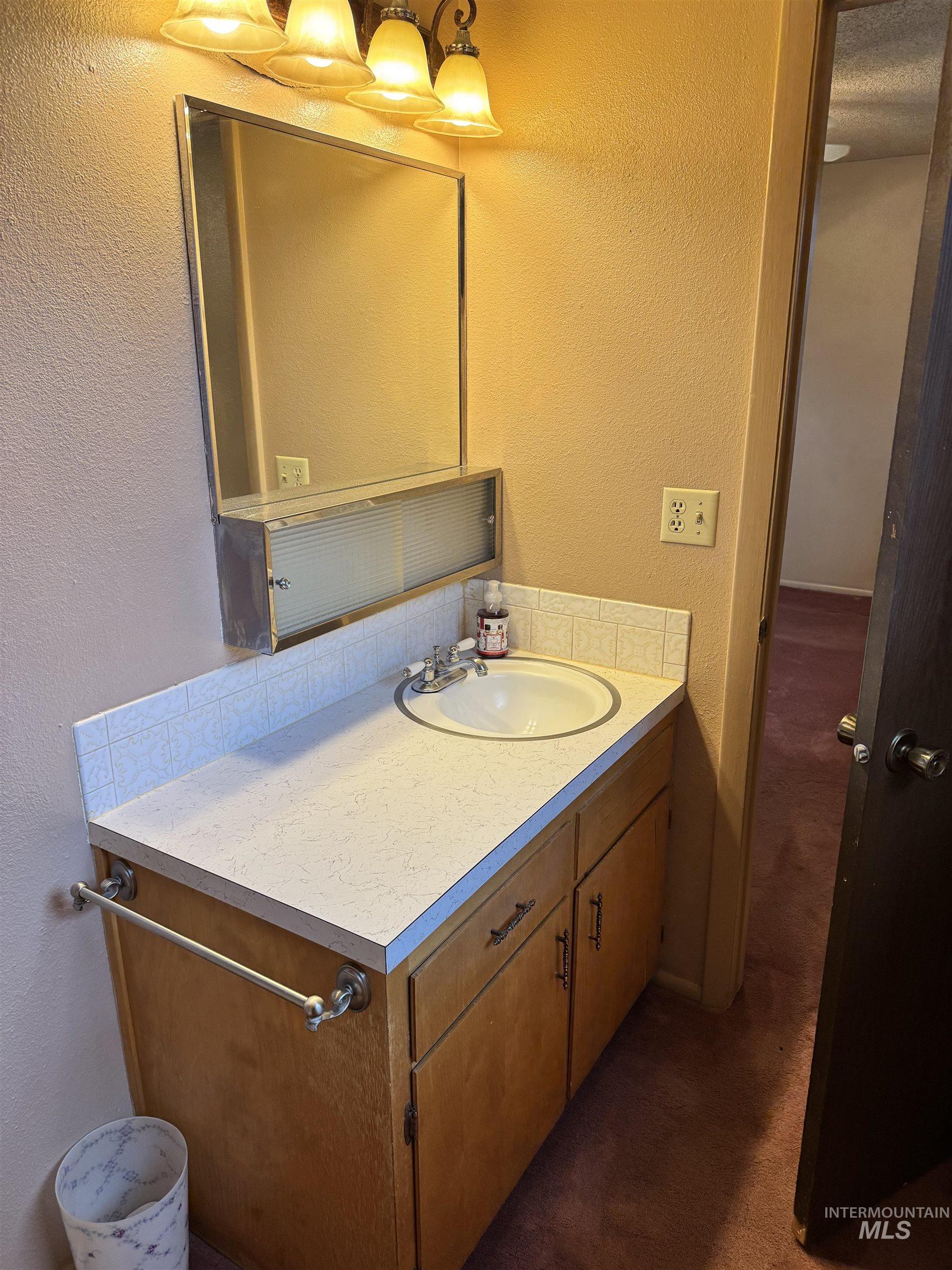 Bathroom with a textured wall and vanity