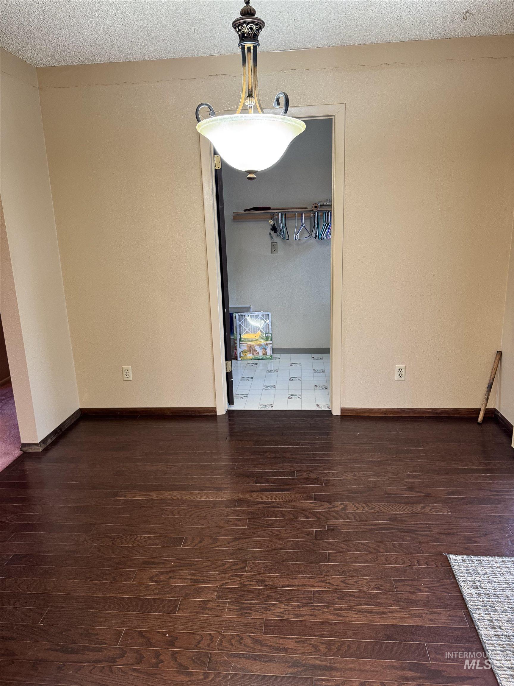 Unfurnished dining area featuring a textured ceiling and dark wood finished floors