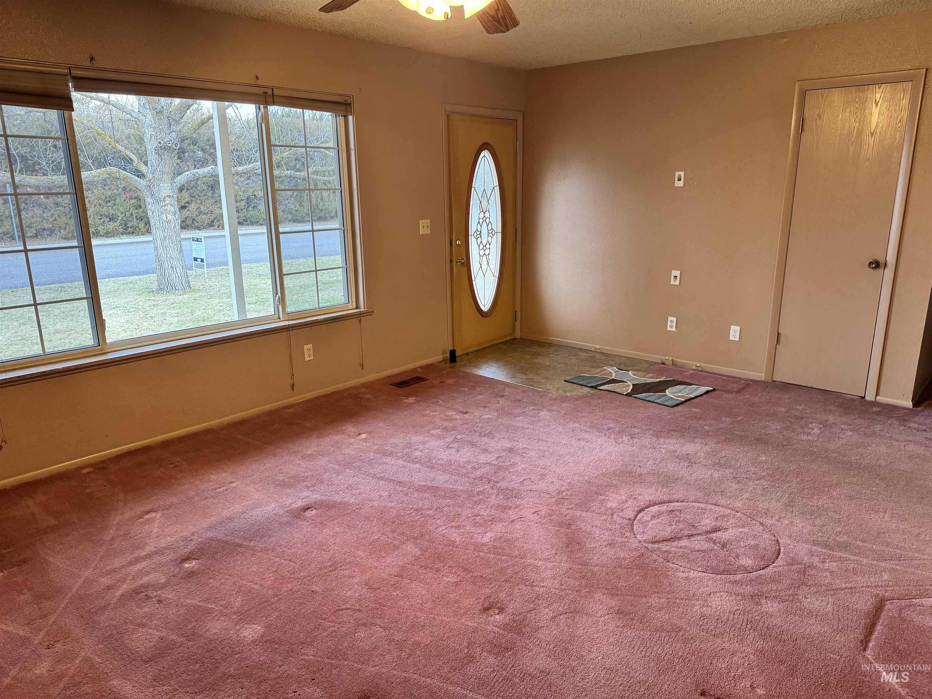 Carpeted foyer with a textured ceiling and a ceiling fan