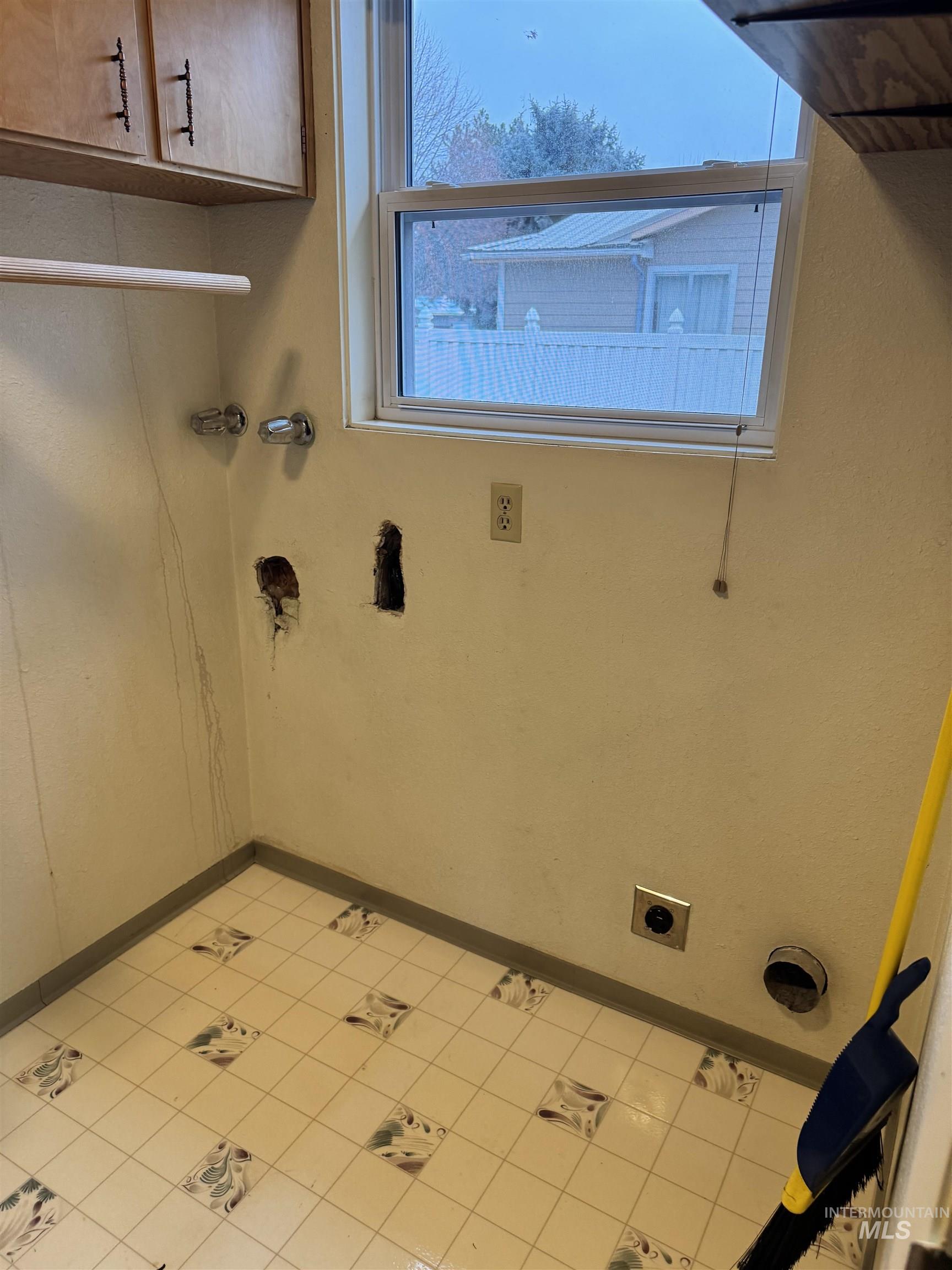 Laundry area with cabinet space and light tile patterned floors