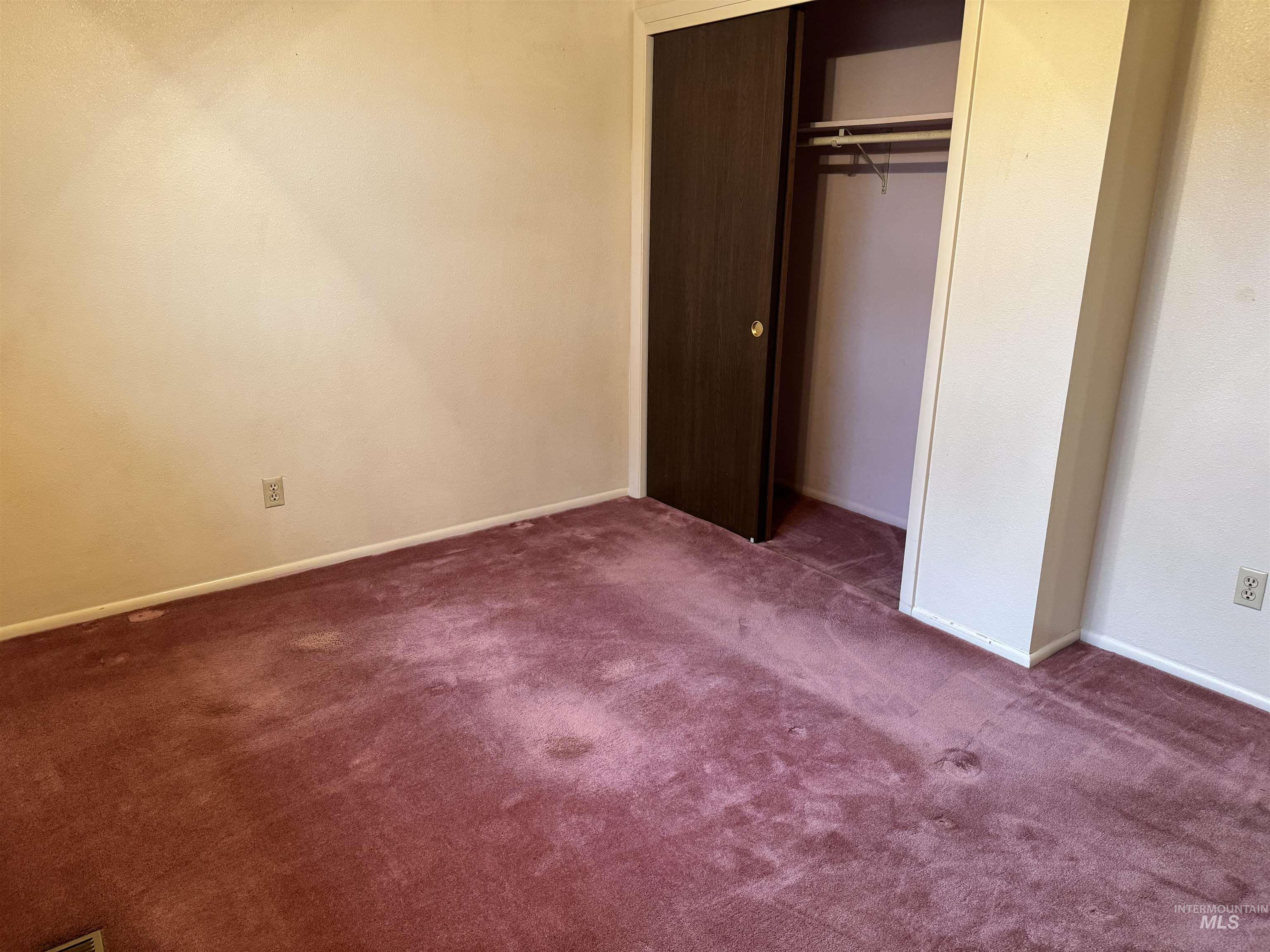 Unfurnished bedroom featuring dark carpet and a closet