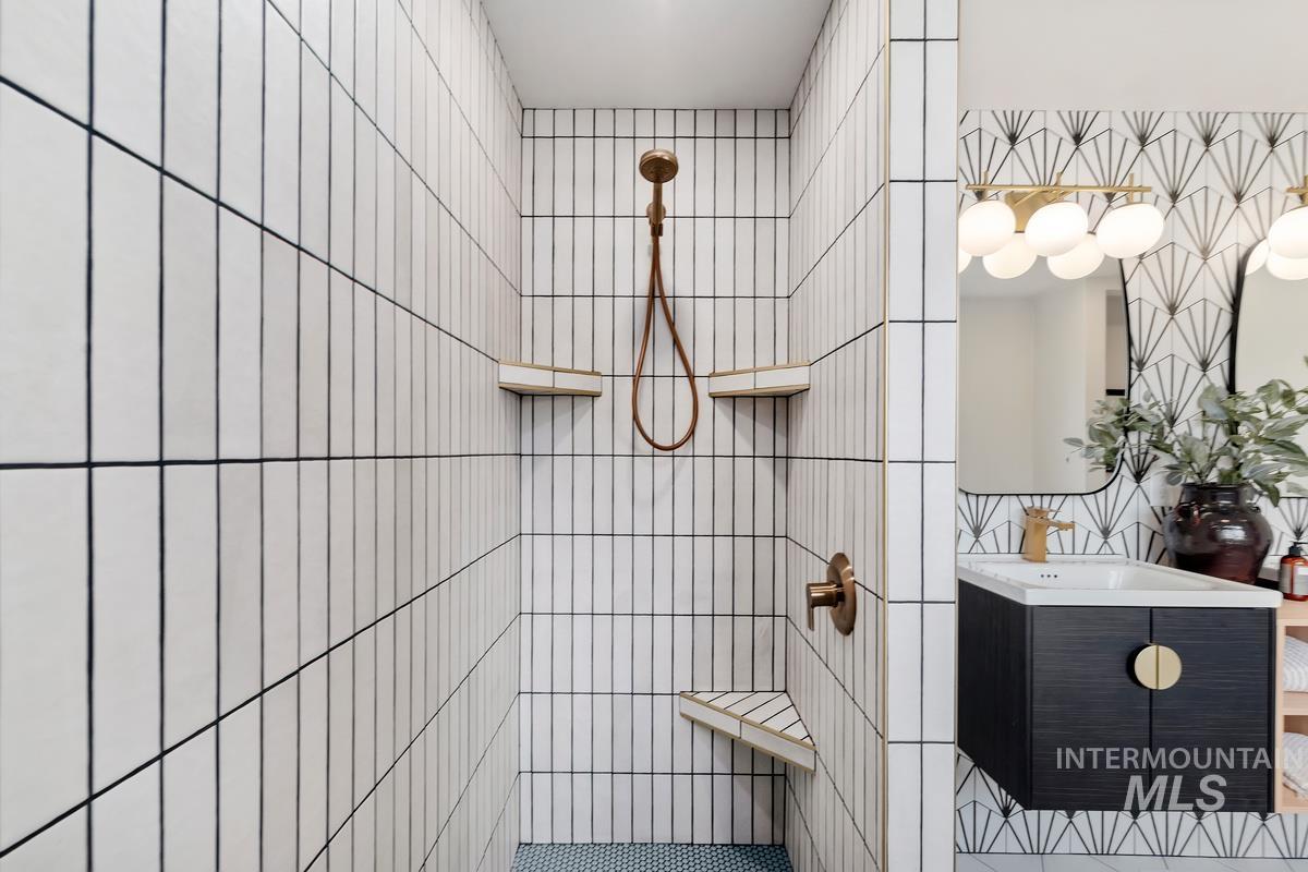 Bathroom featuring tile walls, a tile shower, and vanity