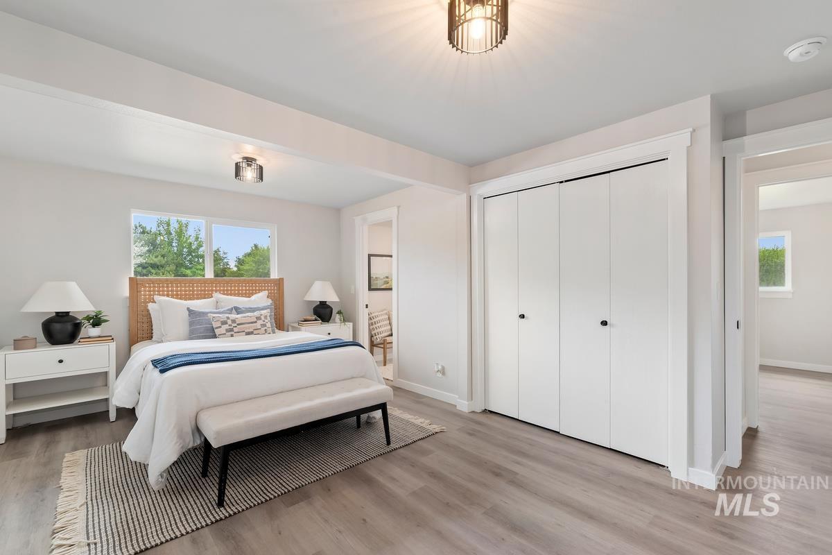 Bedroom with multiple windows, light wood finished floors, and a closet
