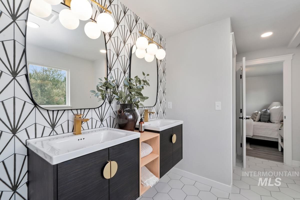 Ensuite bathroom with two vanities, tile patterned floors, and recessed lighting