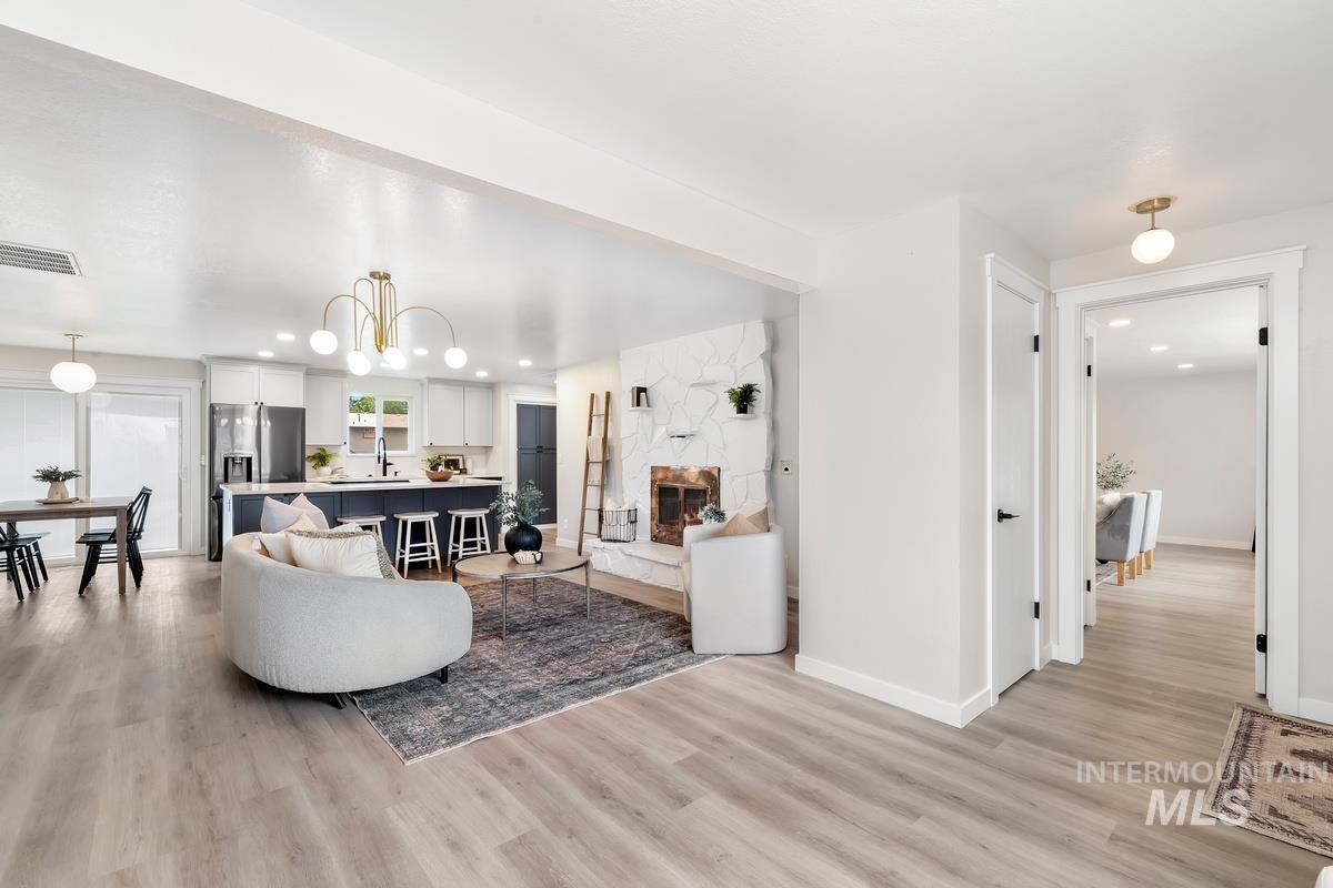 Living room with light wood-type flooring, recessed lighting, a fireplace, and a chandelier