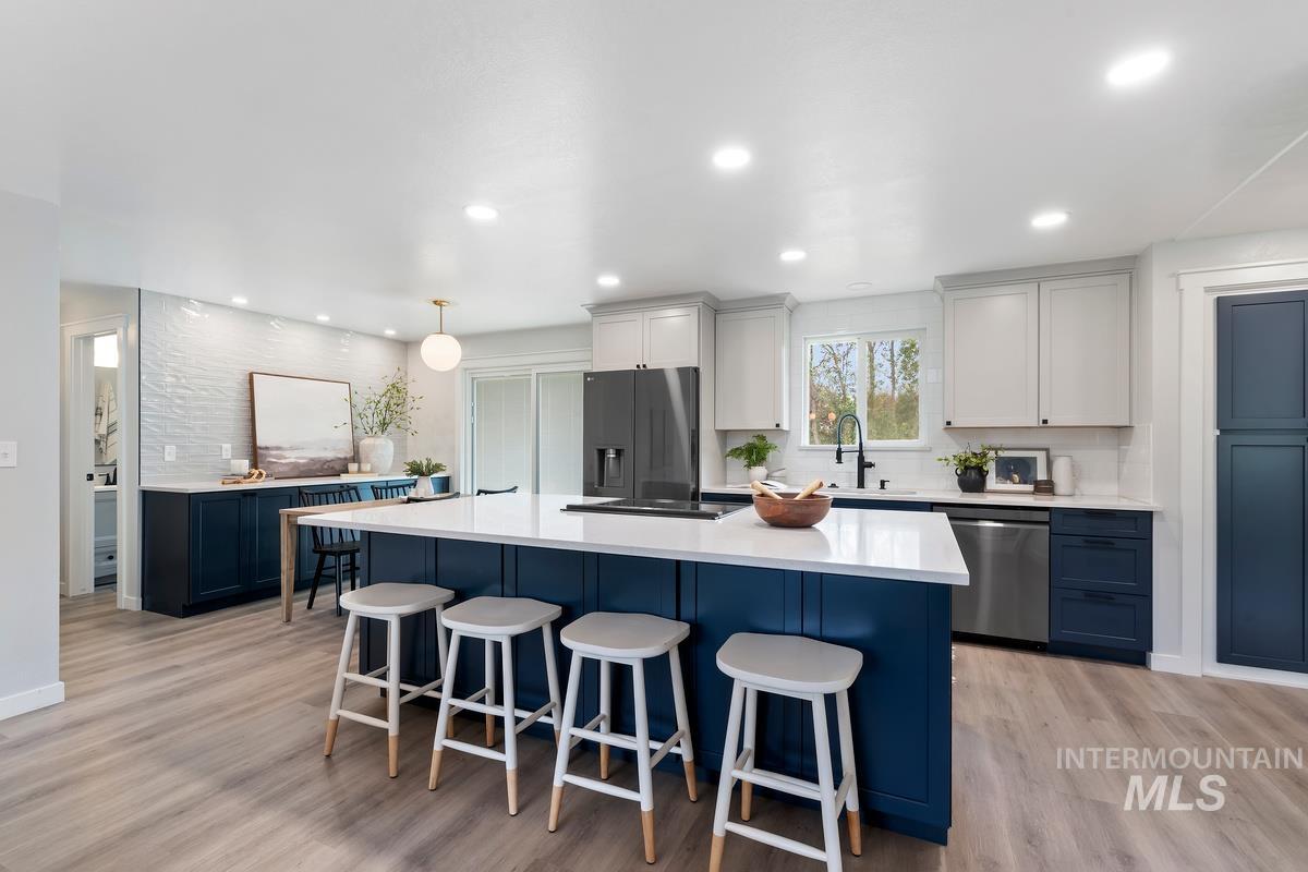 Kitchen with tasteful backsplash, a kitchen bar, light wood-type flooring, a kitchen island, and recessed lighting