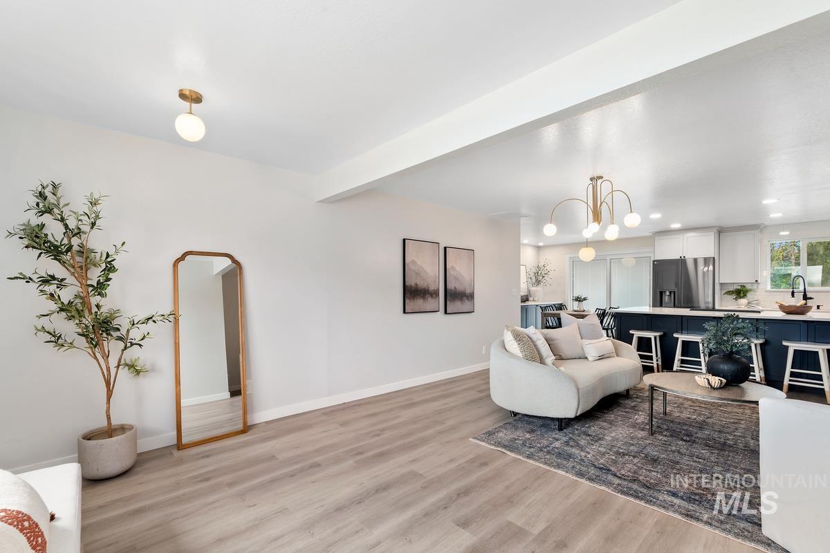 Living room with light wood-type flooring, recessed lighting, beamed ceiling, and a chandelier