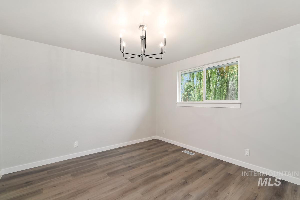 Spare room featuring a chandelier and wood finished floors