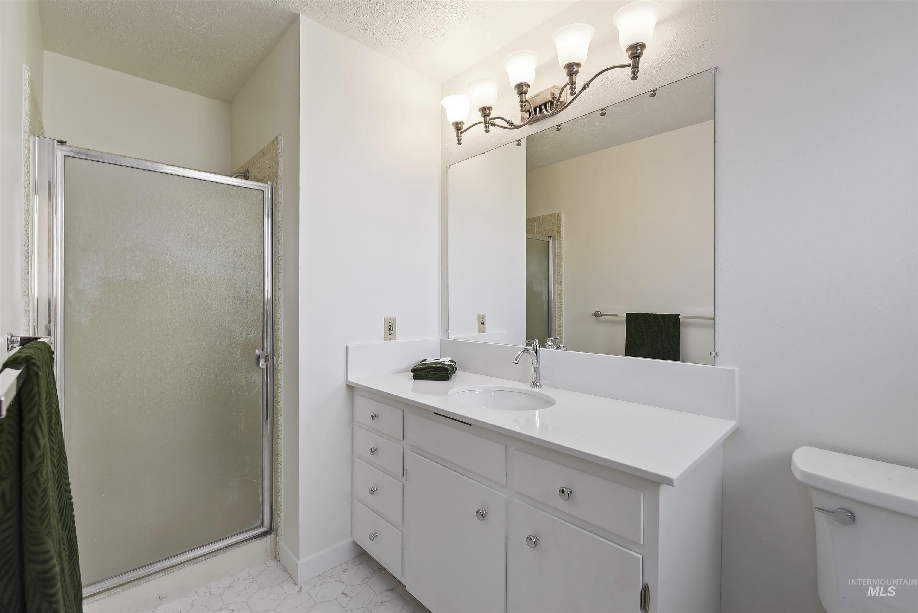 Bathroom with vanity, a stall shower, light tile patterned floors, and a textured ceiling