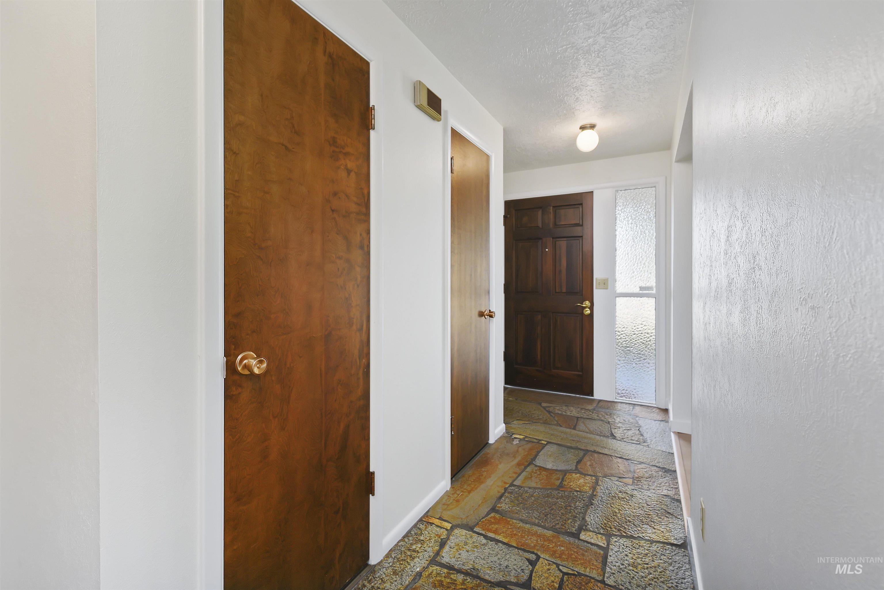 Foyer entrance with a textured ceiling and stone tile flooring
