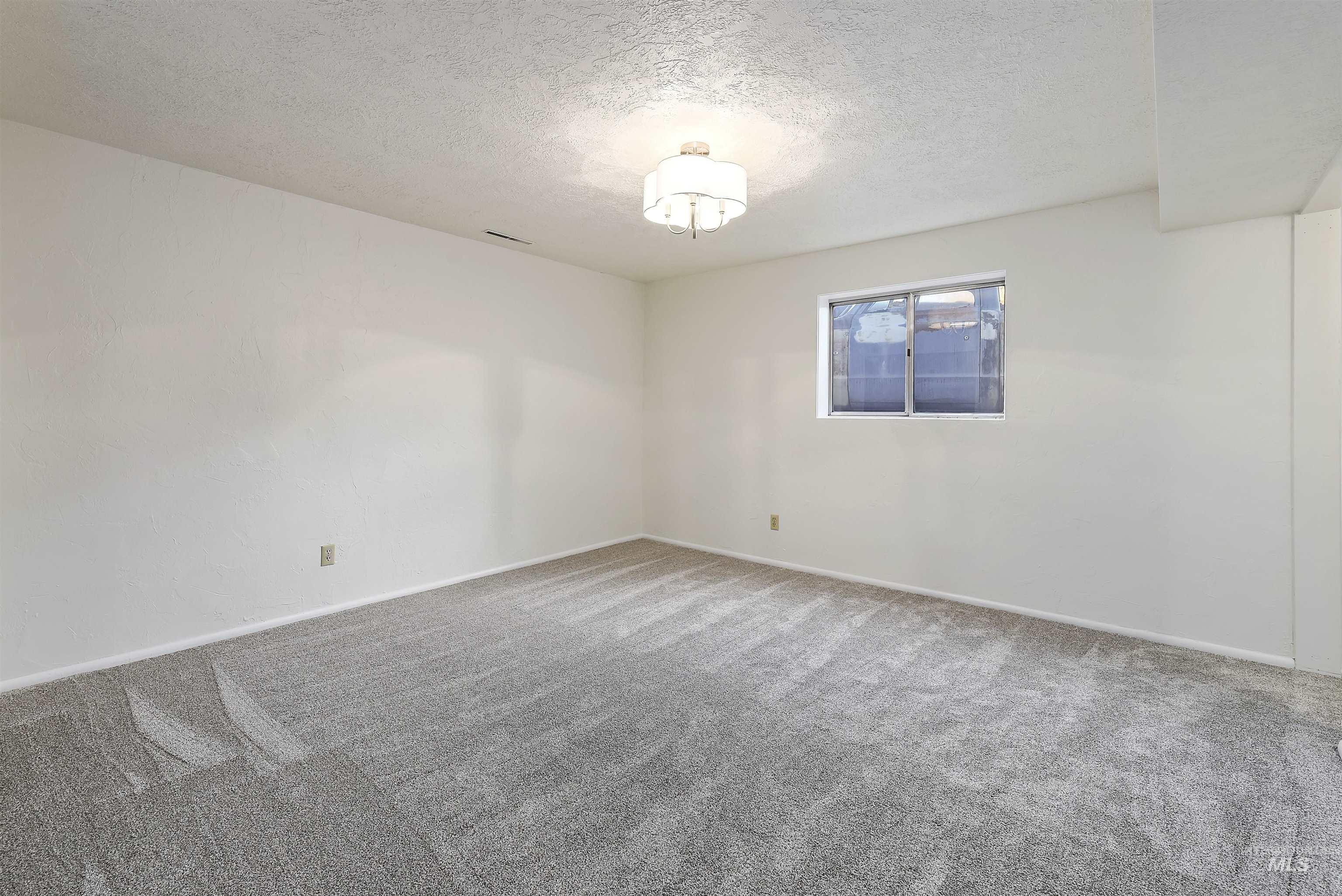 Empty room with carpet floors and a textured ceiling