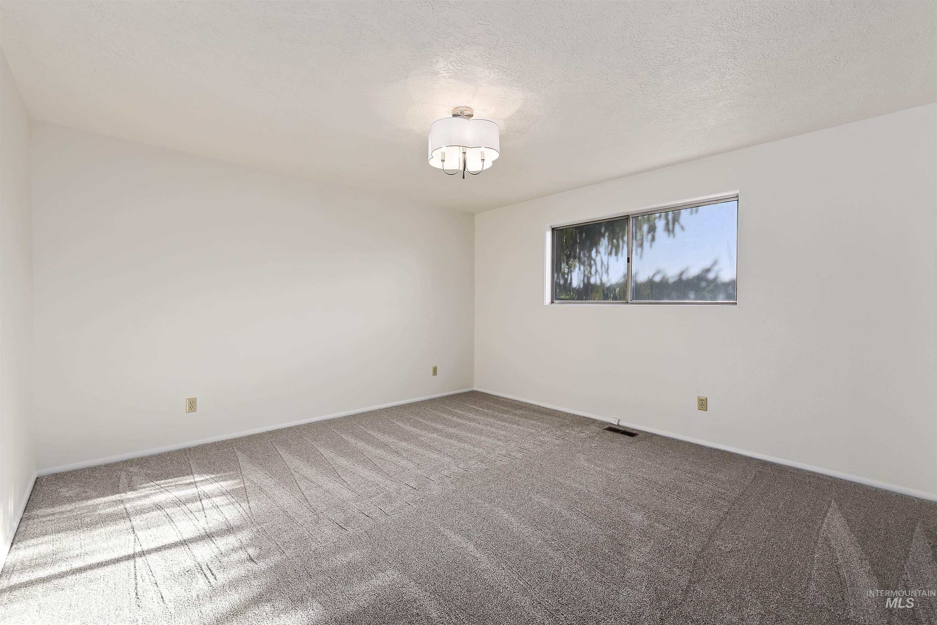 Carpeted spare room with baseboards and a textured ceiling