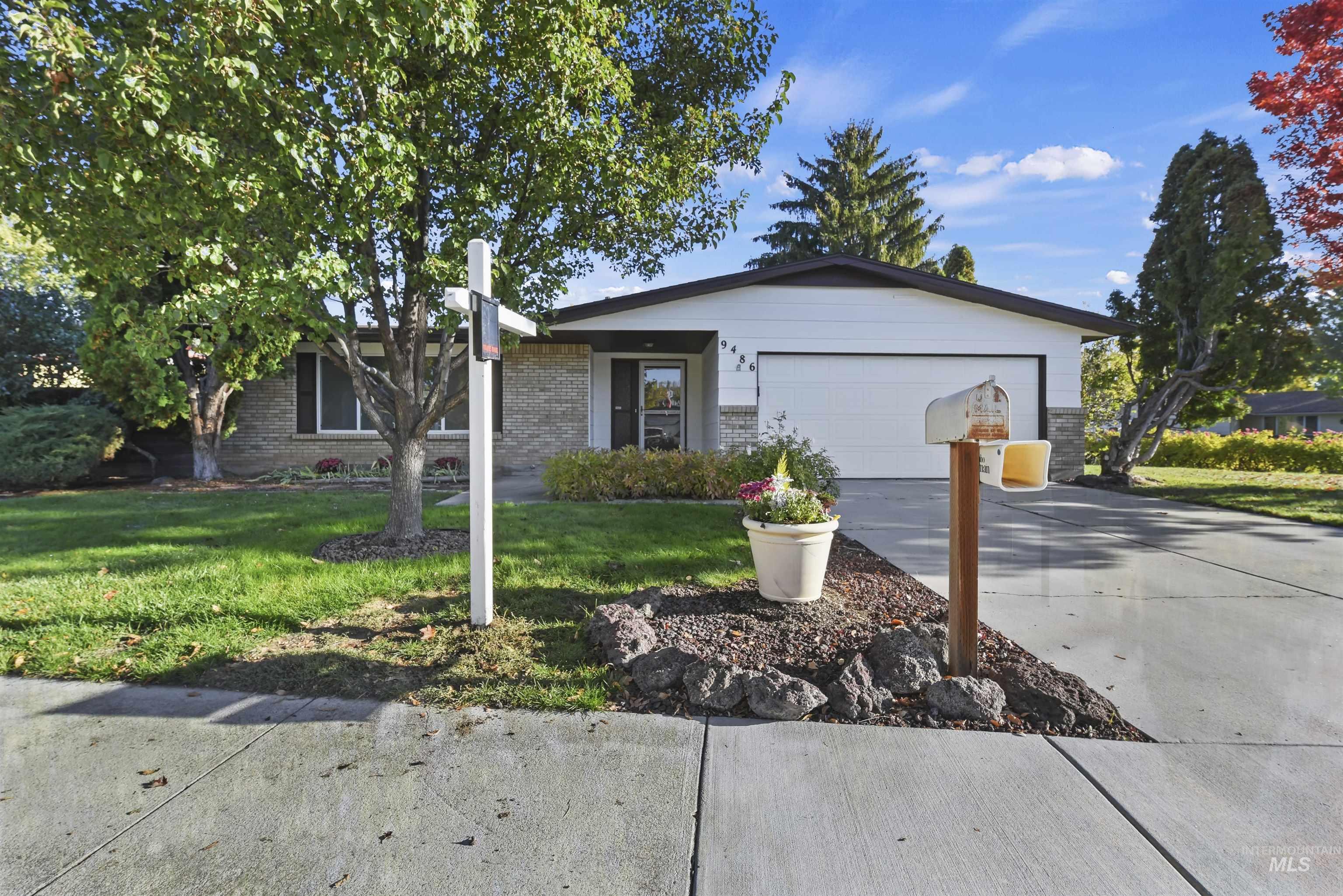 Ranch-style home with a front lawn, brick siding, concrete driveway, and an attached garage