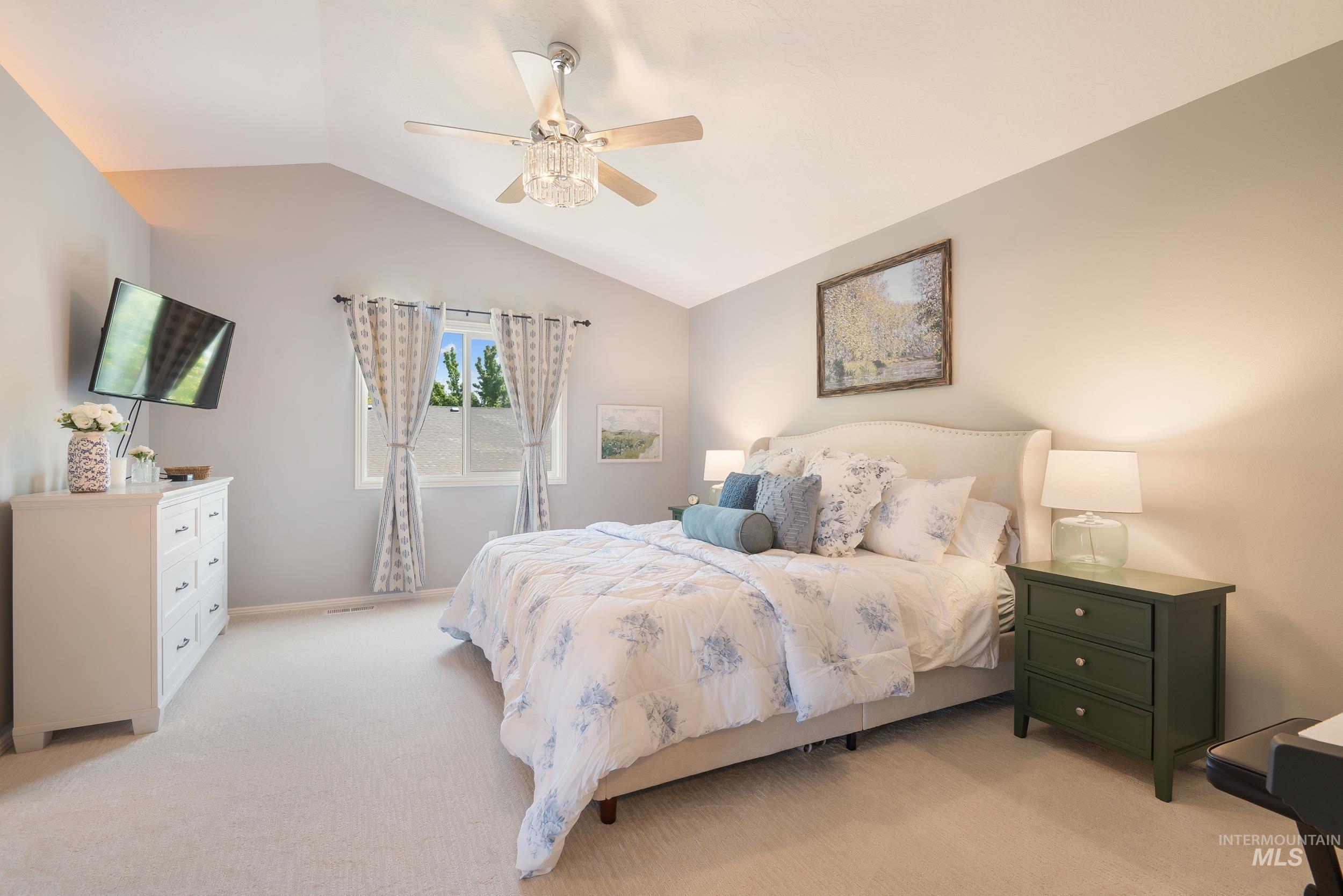 Carpeted bedroom with lofted ceiling and ceiling fan