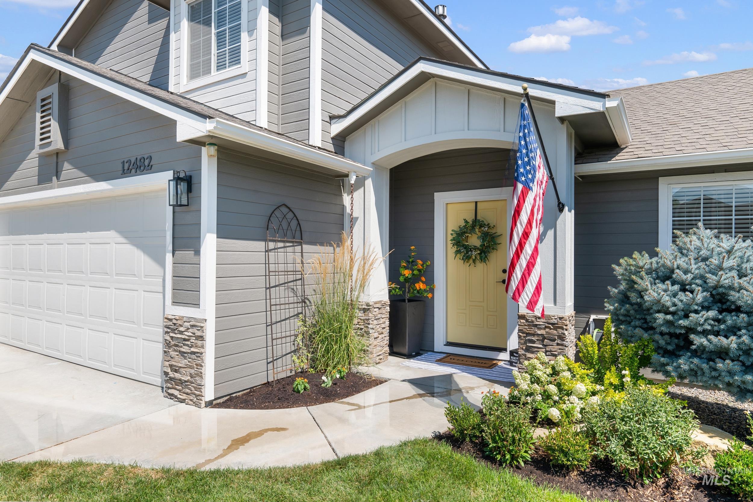 Property entrance featuring stone siding, a shingled roof, board and batten siding, and driveway