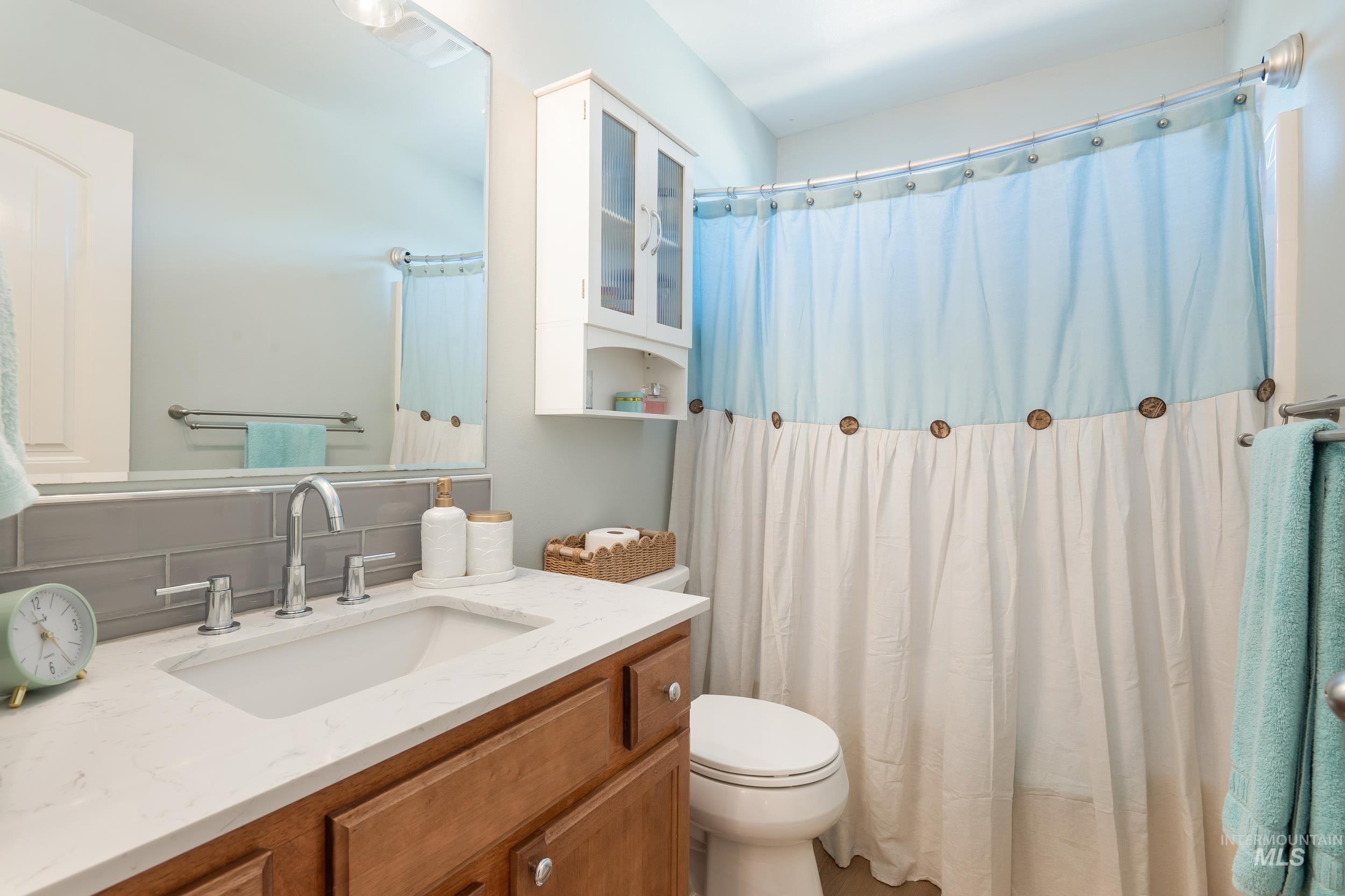 Bathroom featuring vanity, backsplash, and a shower with curtain