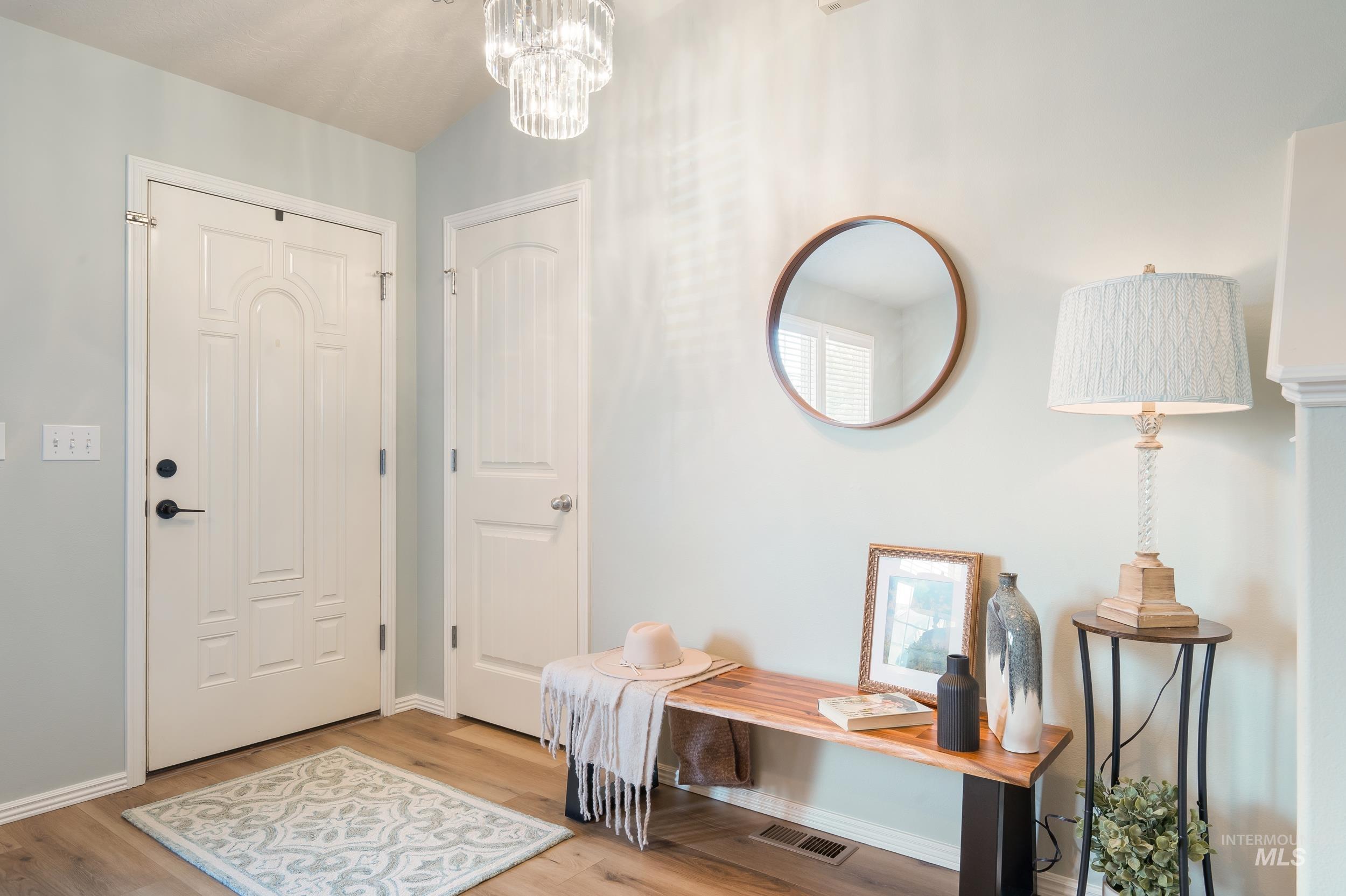 Foyer with light wood finished floors and a chandelier