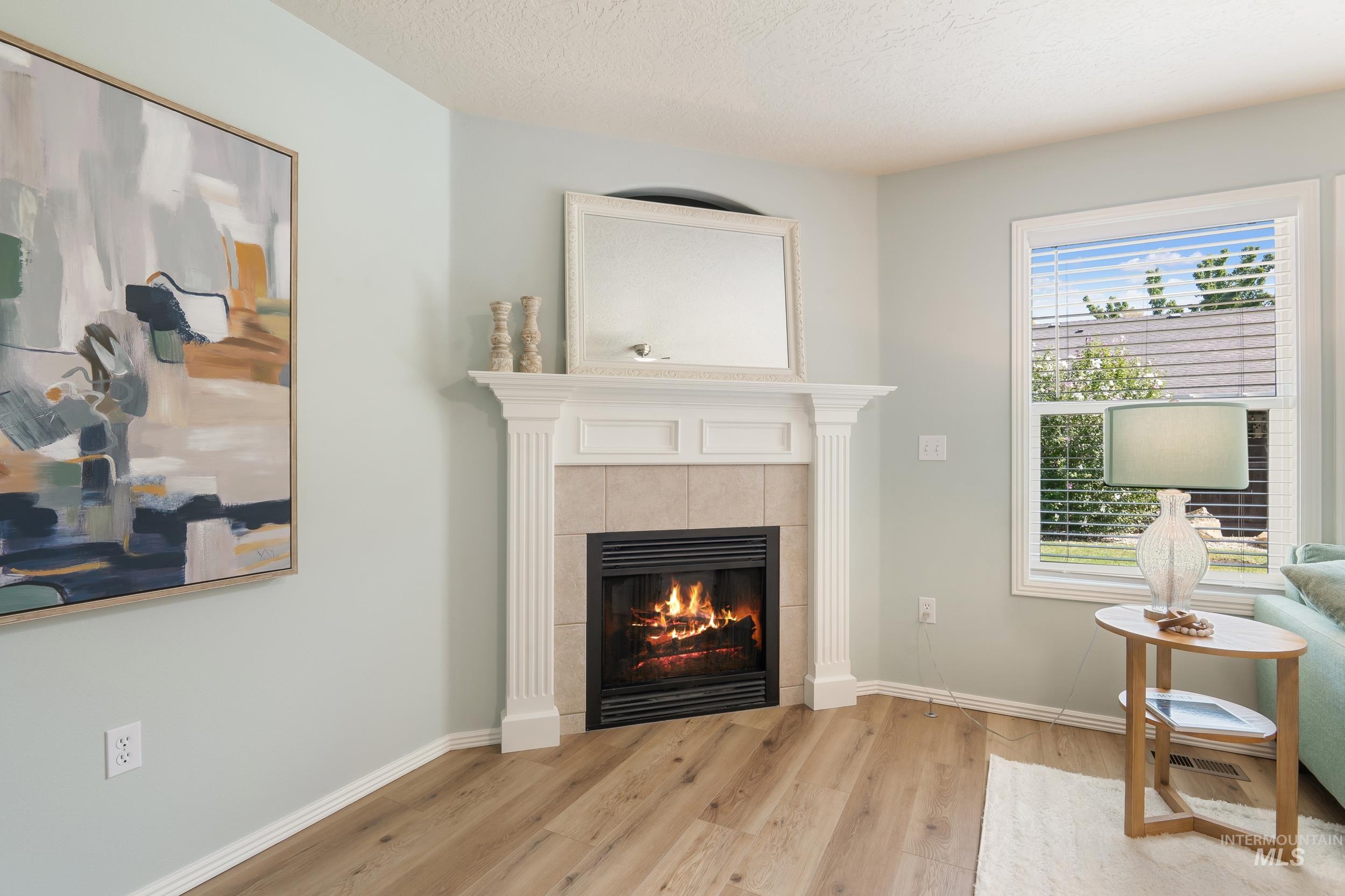 Living room with a fireplace, wood finished floors, and a textured ceiling
