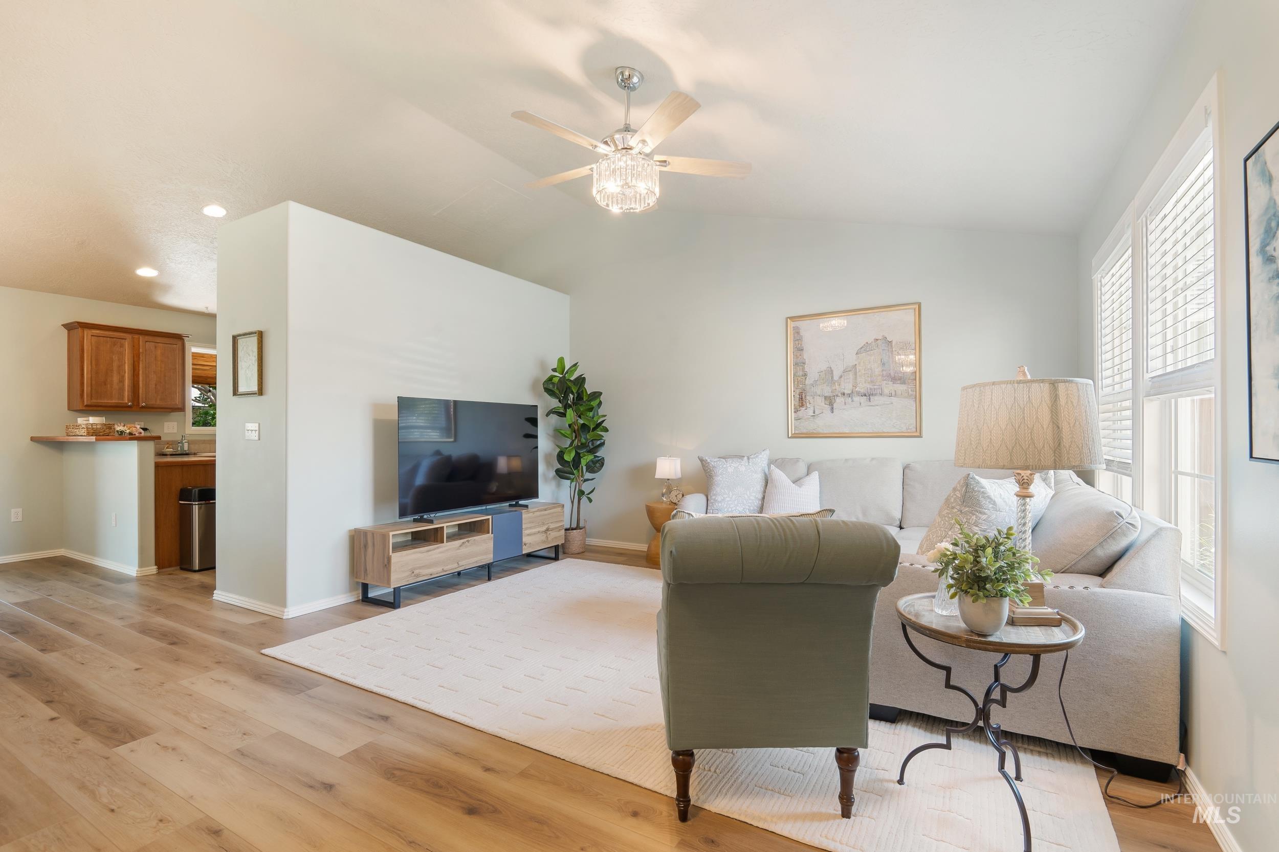 Living area featuring light wood finished floors, lofted ceiling, and ceiling fan