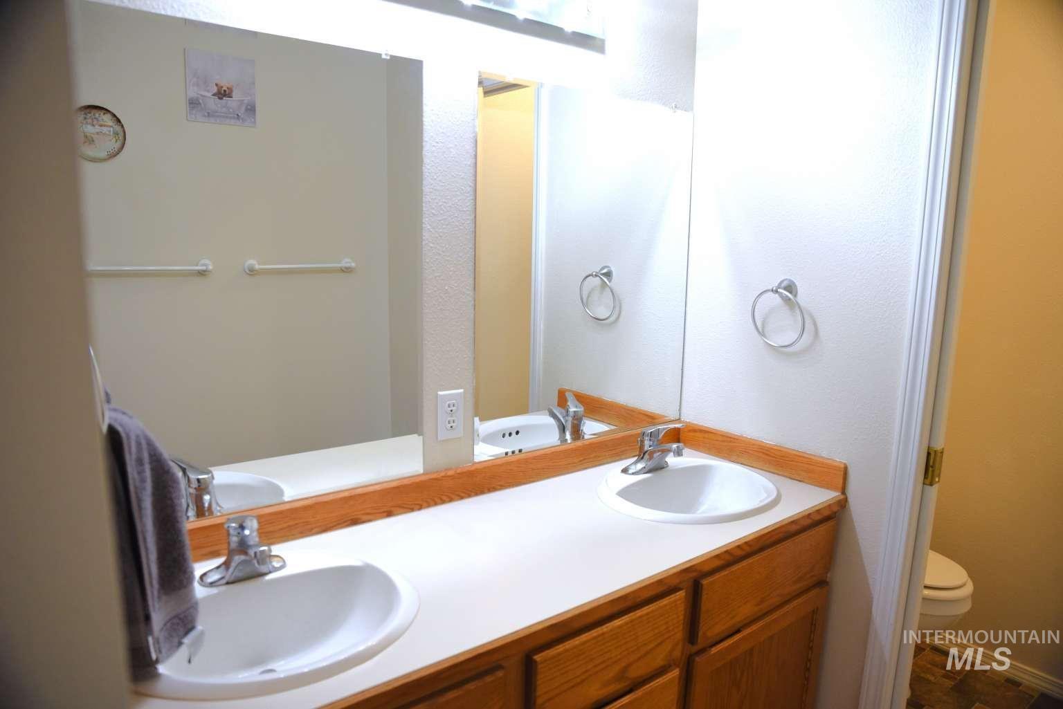 Full bathroom with double vanity and a textured wall