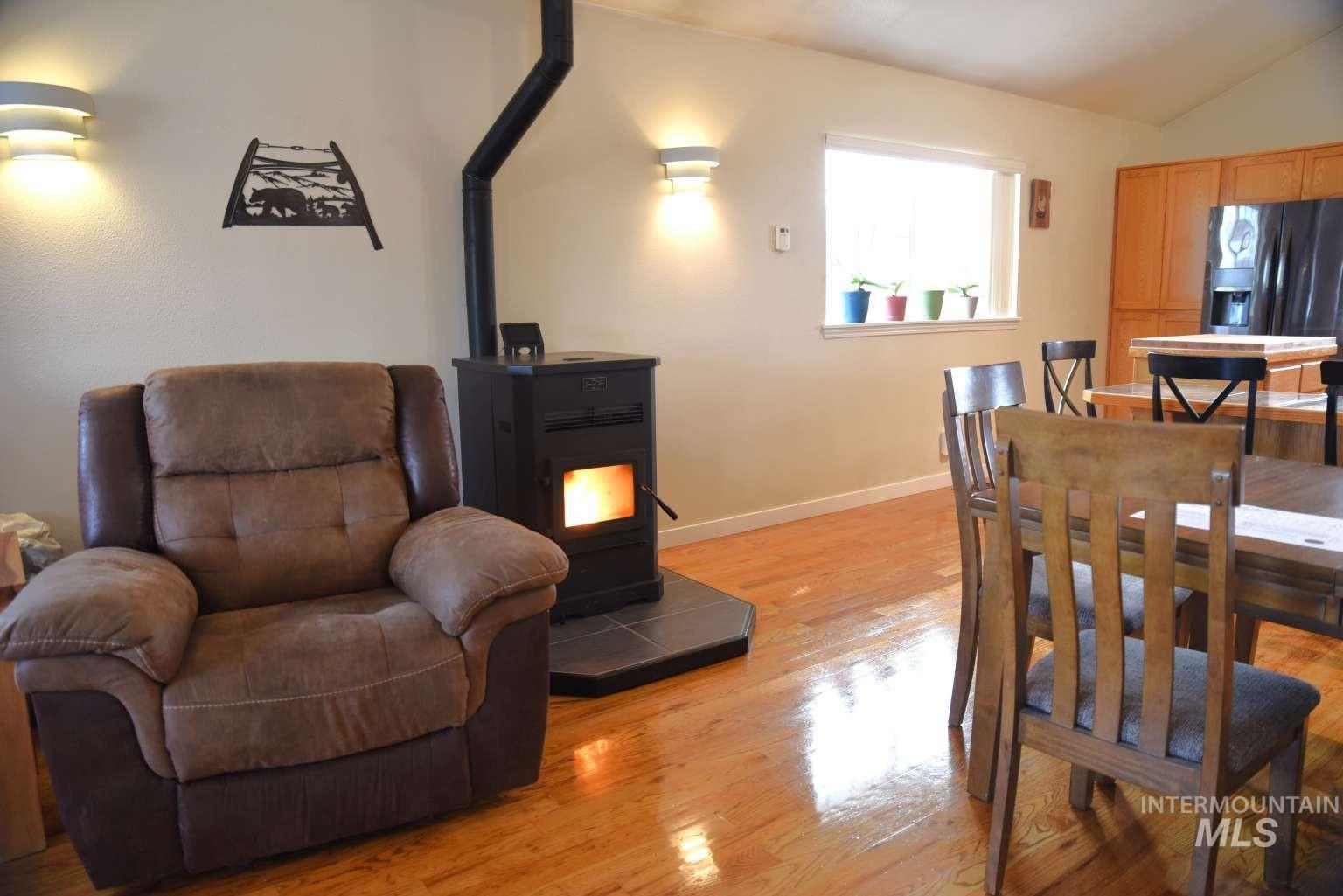 Dining space with light wood-style floors, vaulted ceiling, and a wood stove