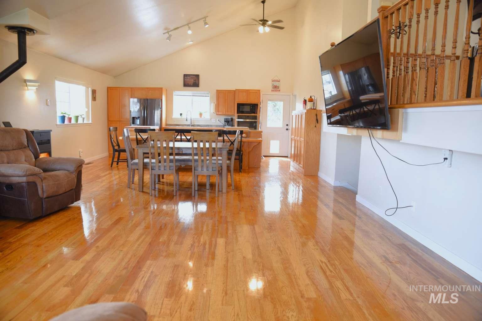 Dining space with a ceiling fan, light wood-style floors, track lighting, and vaulted ceiling