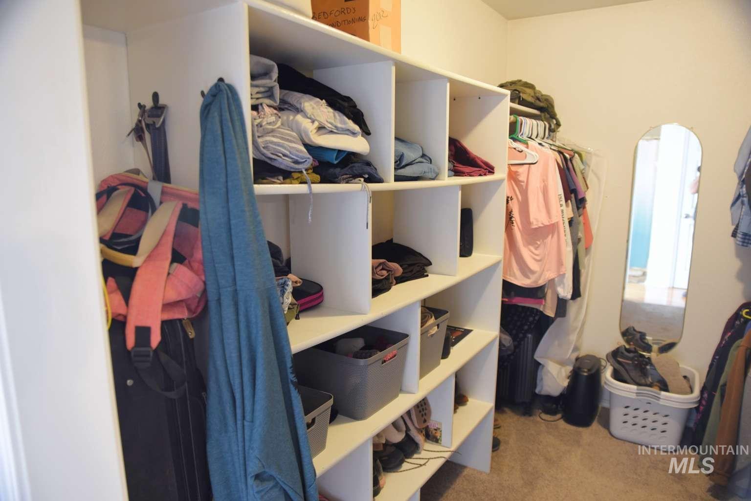 Walk in closet with light colored carpet and arched walkways