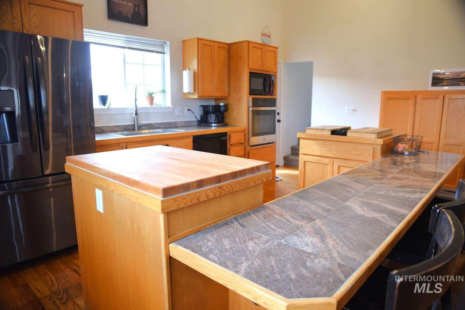 Kitchen featuring black appliances, dark wood-type flooring, a kitchen island, and a kitchen breakfast bar