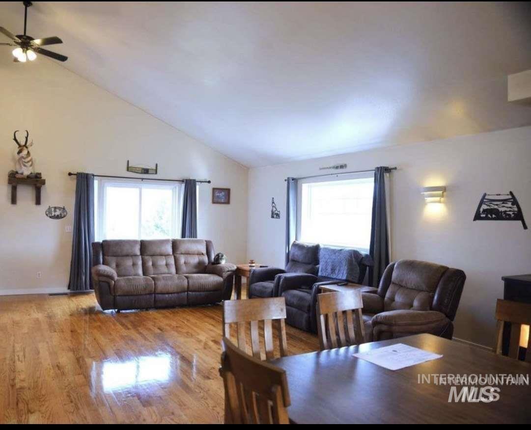 Living area with wood finished floors, vaulted ceiling, and a ceiling fan
