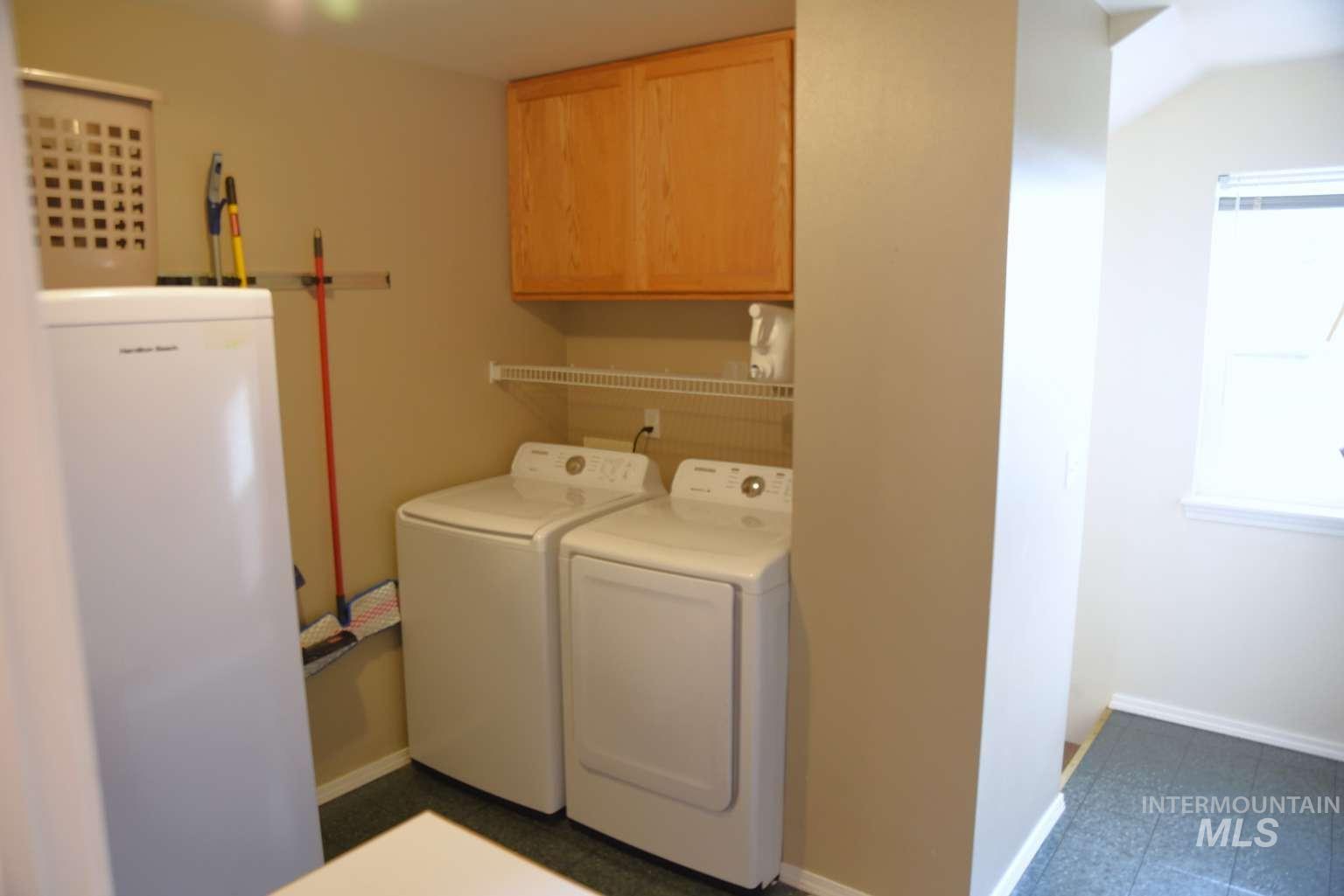 Laundry area featuring cabinet space, washing machine and clothes dryer, and dark flooring
