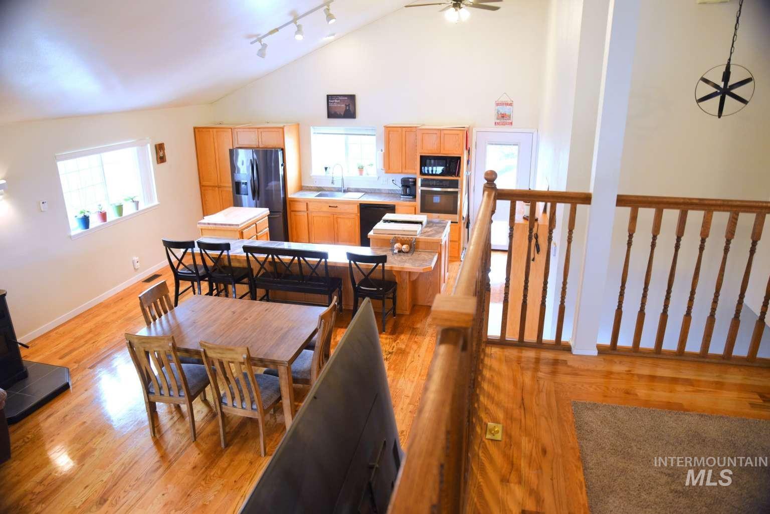 Dining room featuring light wood-style flooring, track lighting, ceiling fan, and lofted ceiling