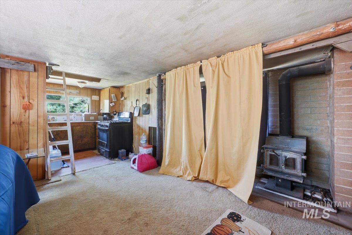 Rustic living area featuring wood-paneled walls and a built-in wood-burning stove within a brick surround