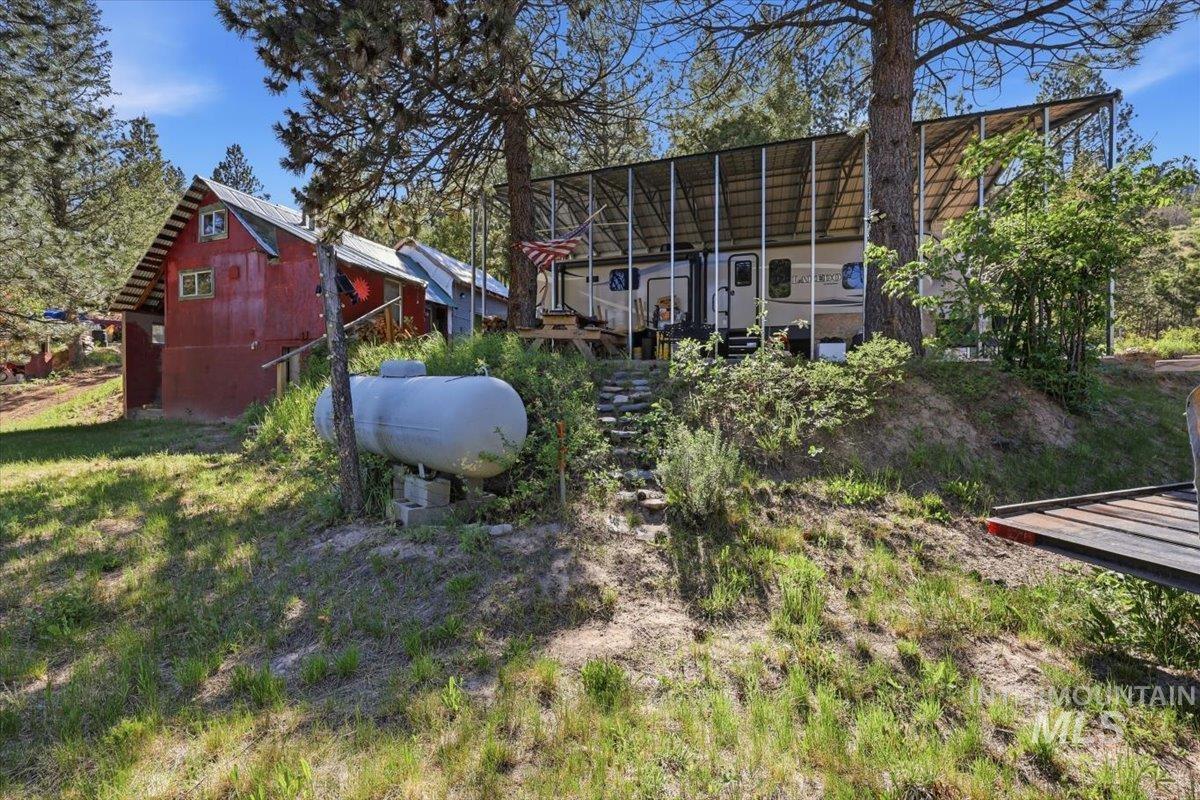 Red corrugated metal siding building with a white propane tank and a tiered stone pathway