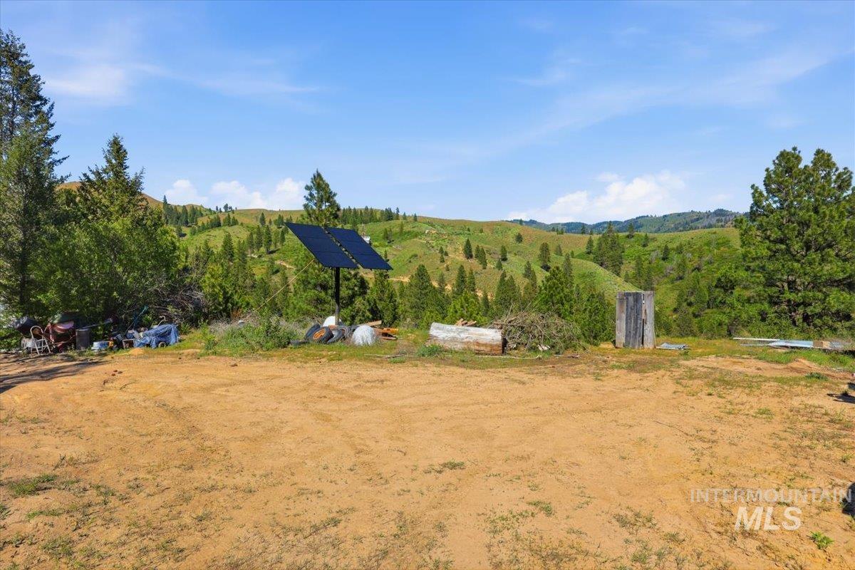Expansive dirt lot providing a clear building site, surrounded by natural hills and mature trees