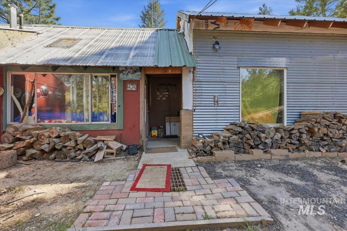 Eclectic exterior featuring a corrugated metal roof, corrugated metal siding, and a red brick paver entry