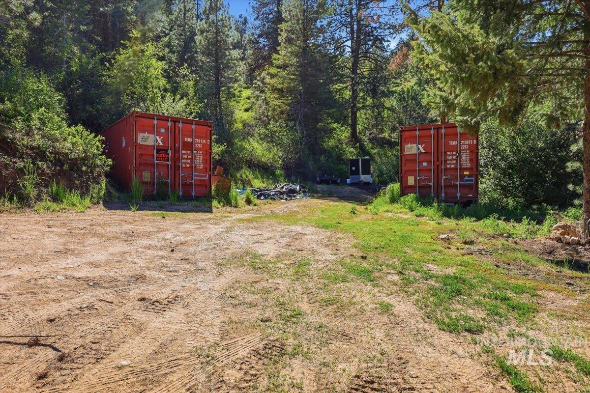 Expansive natural terrain featuring two red storage containers and mature trees