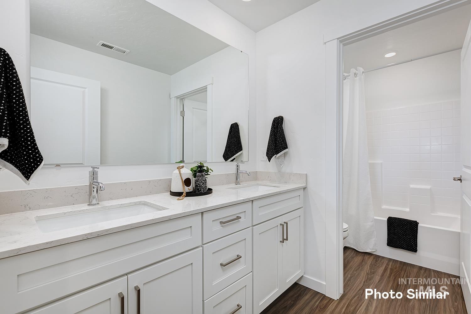 Bathroom with shower / tub combo, double vanity, dark wood finished floors, and recessed lighting