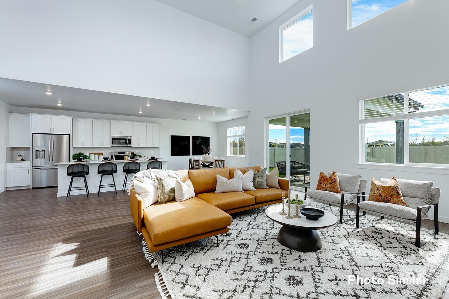 Living area featuring a towering ceiling, light wood-style flooring, and recessed lighting