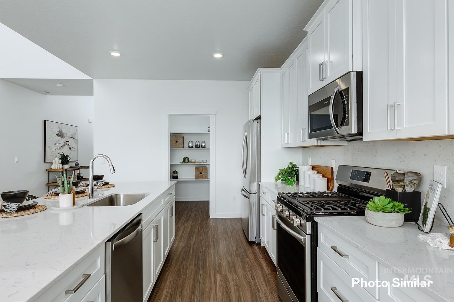 Kitchen featuring light stone counters, stainless steel appliances, dark wood-type flooring, white cabinetry, and recessed lighting