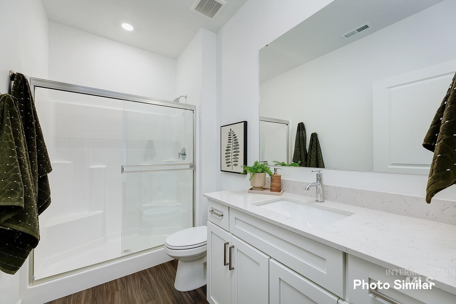 Bathroom with a stall shower, vanity, and dark wood-style flooring