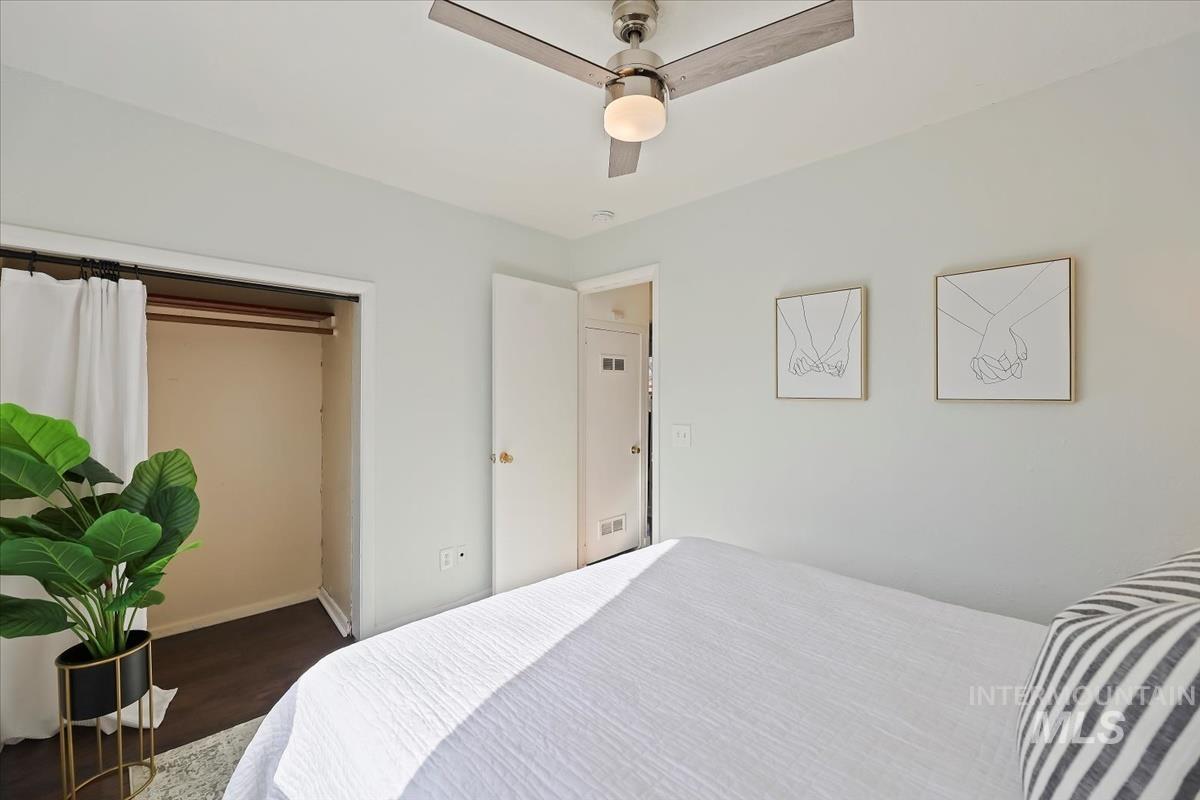 Bedroom with ceiling fan, dark wood-style flooring, and a closet