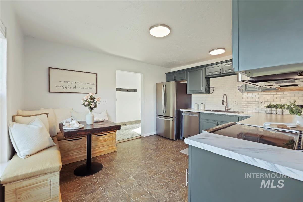 Kitchen featuring light countertops, stainless steel appliances, decorative backsplash, and gray cabinetry