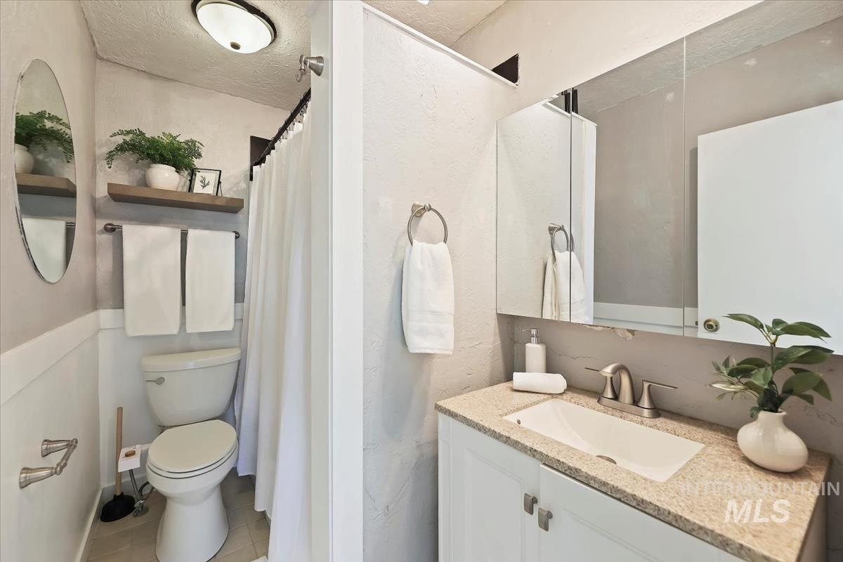 Bathroom featuring vanity, a shower with shower curtain, light tile patterned floors, and a textured ceiling