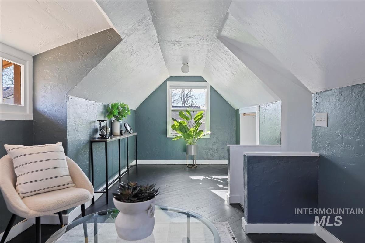 Living area featuring a textured wall, wood-type flooring, and a textured ceiling