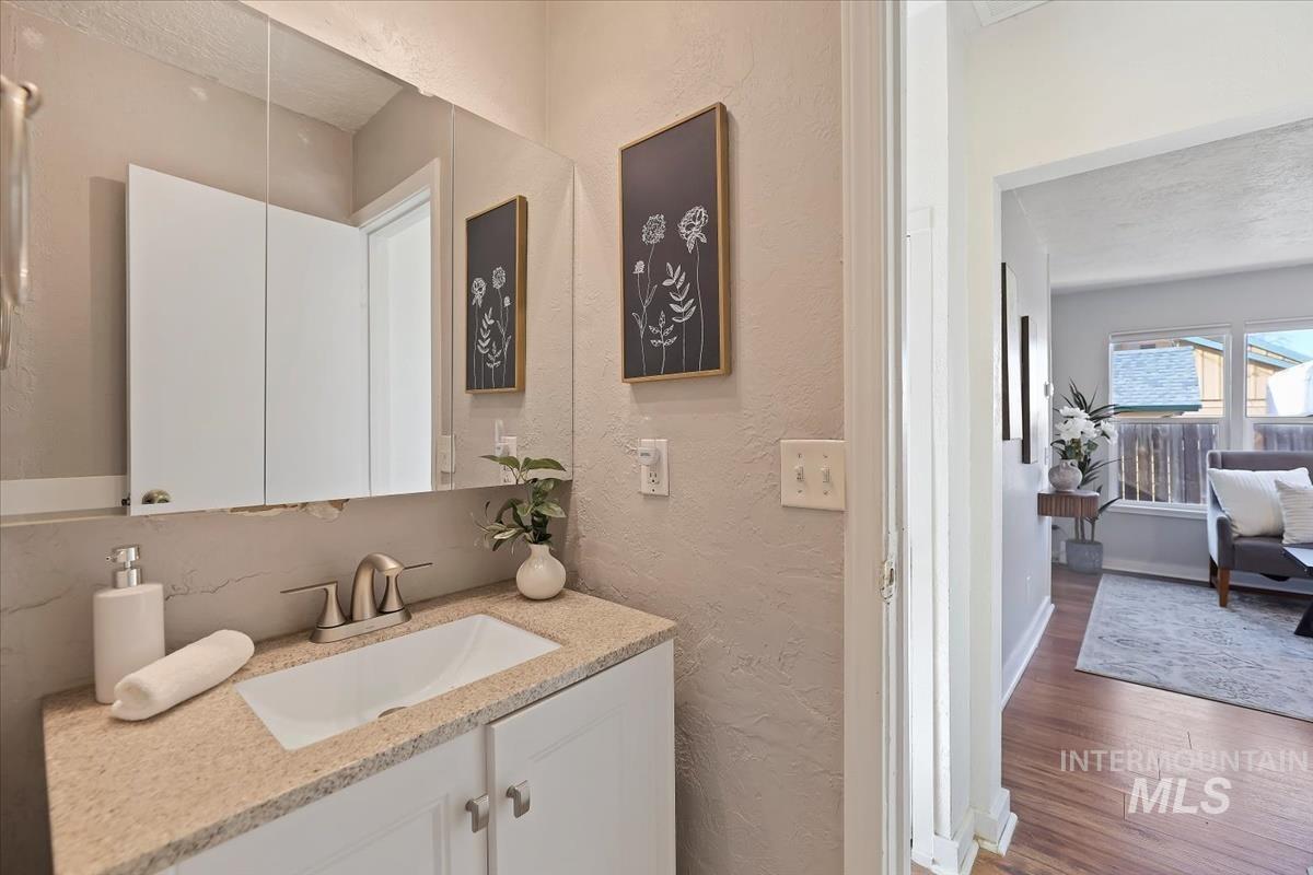 Bathroom with a textured wall, vanity, wood finished floors, and a textured ceiling