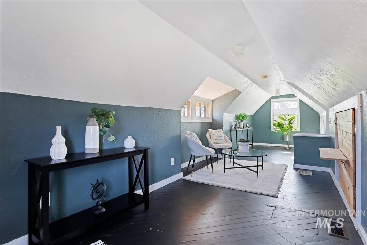 Living area with dark wood-style flooring and vaulted ceiling