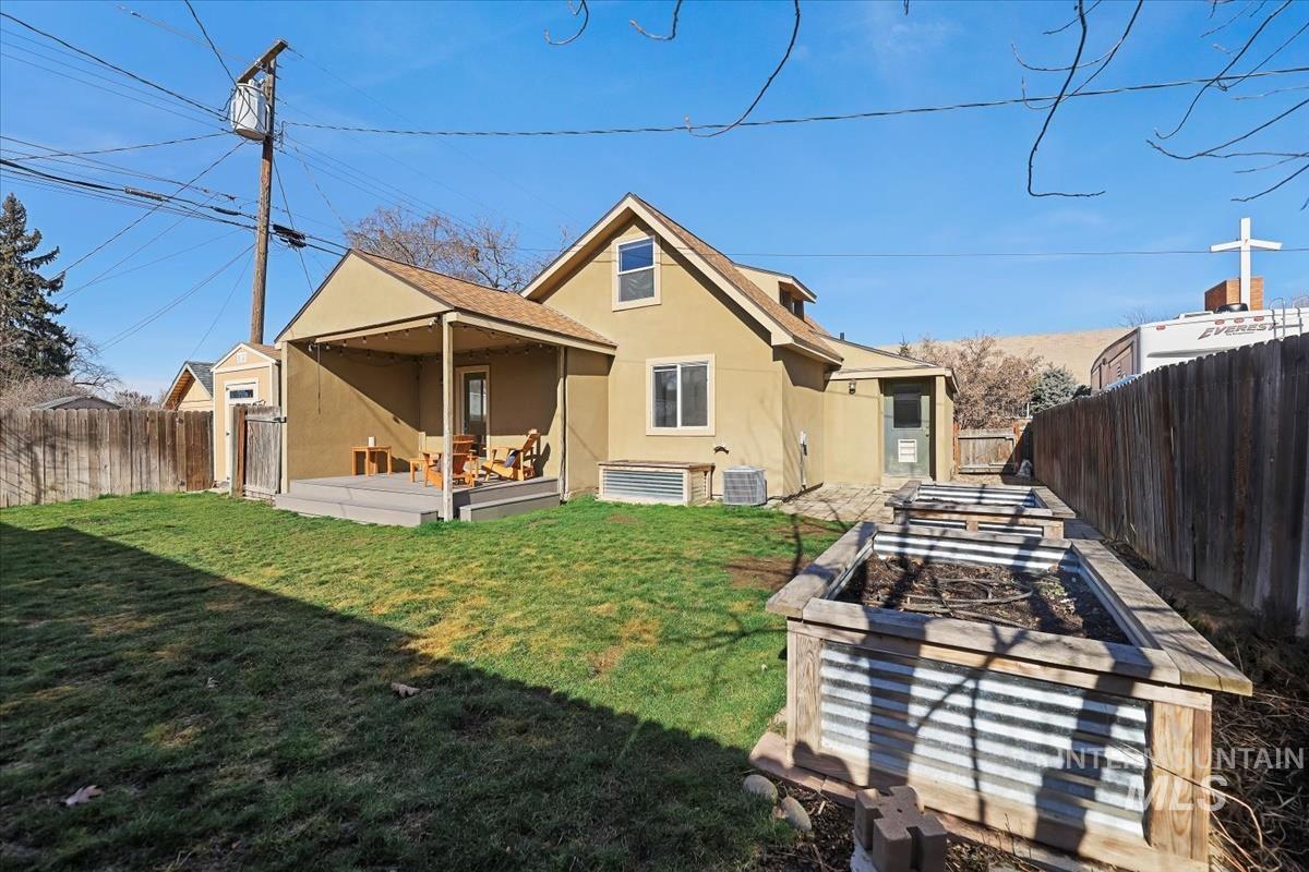 Back of house featuring stucco siding, a fenced backyard, a patio, and a vegetable garden