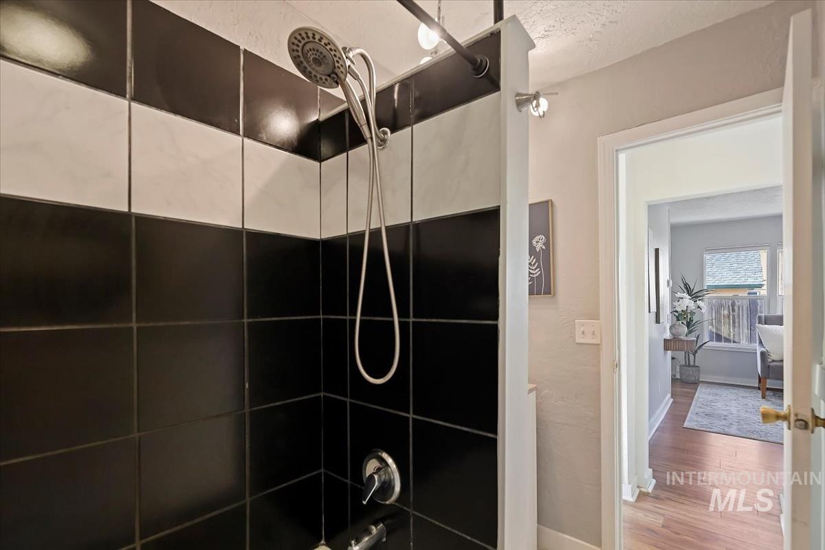 Full bathroom with shower / bath combination, wood finished floors, and a textured ceiling